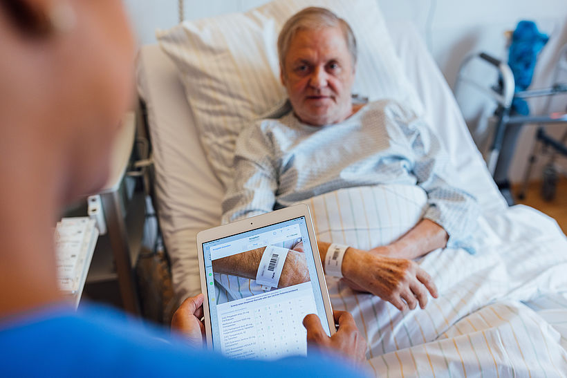 Der Bedside-Scan schließt den letzten offenen Schritt im digitalen Prozess: Am Krankenhausbett scannt die Pflegekraft sowohl das Patientenarmband als auch den Medikamentenbeutel. Das System gleicht die Daten in Echtzeit mit der Verordnung ab. Stimmt etwas nicht, wird die Gabe gestoppt. 